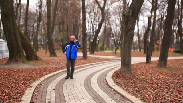 Adult man talking on  mobile in   autumn park