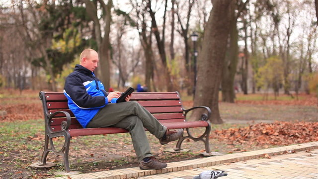 Adult man working on a tablet  in  park