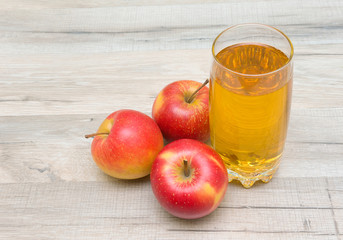 ripe red apples and glass of juice on a wooden table