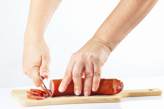 Hands sliced salami on a cutting board close up