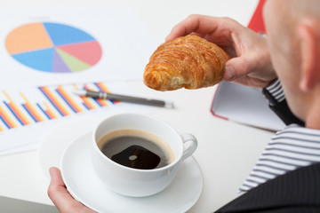 Man in suit with coffee and roll