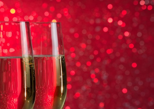 pair of a champagne flutes on red light bokeh background