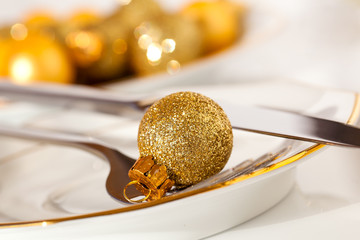 silver cutlery decorated with a golden Christmas bauble