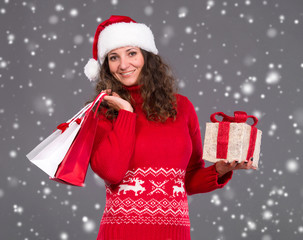 Smiling woman in santa hat with shopping bags and gift box