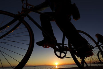 Naklejka na ściany i meble silhouette of the cyclist riding a road bike at sunset