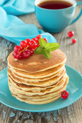 Homemade pancakes with honey and berries on a wooden table.