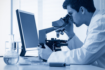 male chemist working with microscope in laboratory