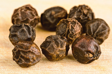 Whole black pepper corns on cutting board