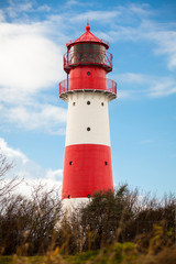 rot weisser leuchtturm vor blauem himmer wolken ostsee