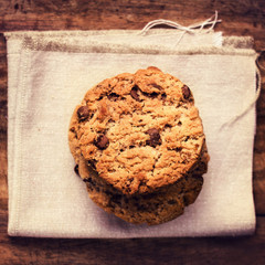 Stacked chocolate chip cookies on white linen napkin on wooden t