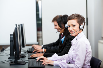 Callcenter Mitarbeiter mit Kopfhörern am Computer freundlich - obrazy, fototapety, plakaty