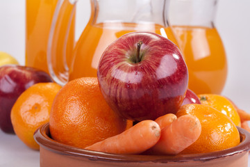 apple, orange and carrots with fresh juice in the background