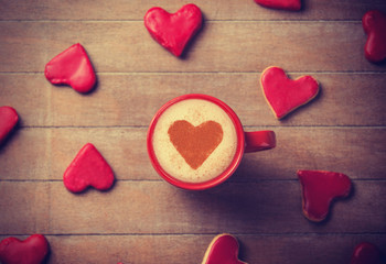 Fototapeta na wymiar Filiżanka kawy z symbolem serca i cukierki wokół.