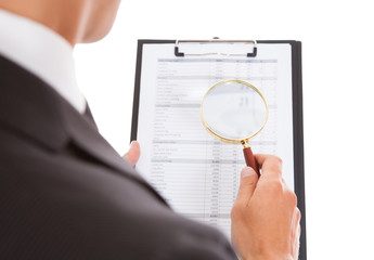 Man Looking Through Magnifying Glass On Clipboard