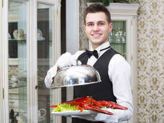 waiter with lobster on a plate in a restaurant