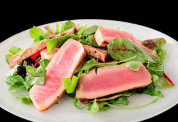 Appetizer with rare fried tuna isolated on black