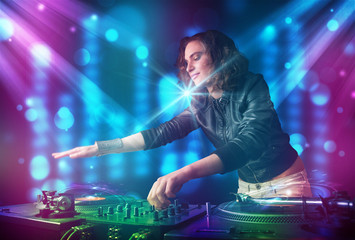 Fototapeta na wymiar Dj girl mixing music in a club with blue and purple lights