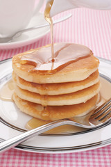 Buttermilk pancakes with maple syrup being poured