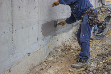 Construction workers with brush applied hydro insulation