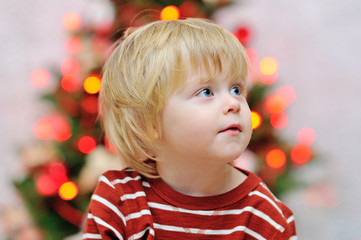 Cute toddler portrait with Christmas tree lights in background