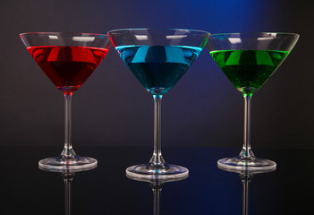 Alcoholic cocktails in martini glasses on dark blue background