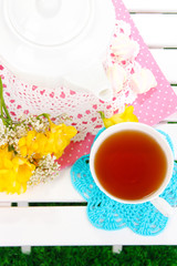 Beautiful set with tea on wooden picnic table close-up