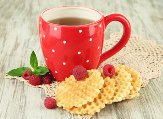 Cup of tea with cookies and raspberries on table close-up