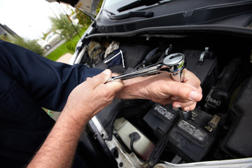 Hands of auto mechanic with wrench.