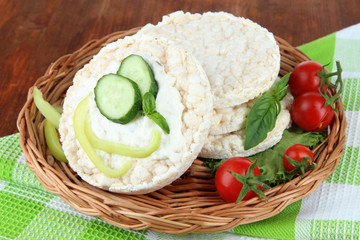 Tasty crispbreads with vegetables on wooden background