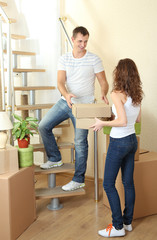 Fototapeta na wymiar Young couple with boxes in new home on staircase
