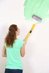 Young woman paints wall in new flat