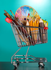 School supplies in supermarket cart on blackboard background
