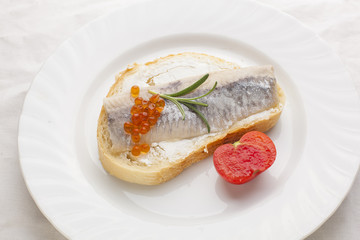 Sandwich with herring fish and caviar on bread, cherry tomato