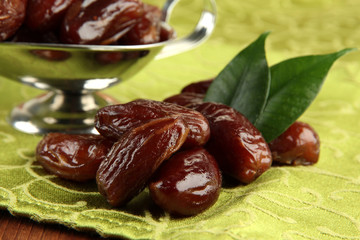Dried dates in metal dish on fabric background