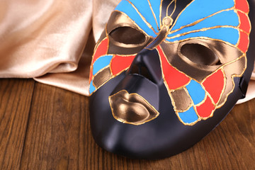 Mask on golden fabric on wooden background