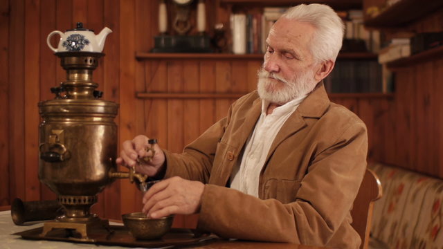 white haired old man drinking tea from a samovar self boiler
