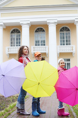 A mother and two children with open umbrellas