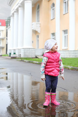 Happy girl in bright clothes standing in a puddle