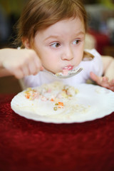 Little girl with a surprised expression on her face eating spagh