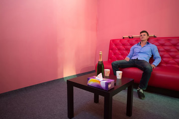 Fototapeta premium A man is sitting on a red couch in a room