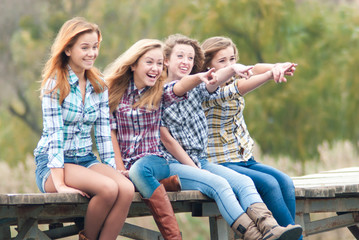 Four girls sitting on river bridge