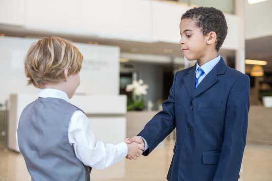 Caucasian Boy And Boy In Business Clothes Shake Hands