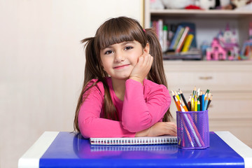 little girl sitting in the children room at the table with color