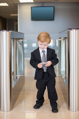 A boy in suit at entrance to business center with card