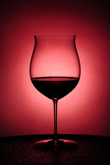 Red wine in glass against red background