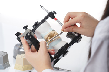 Dental technician working with articulator in dental laboratory