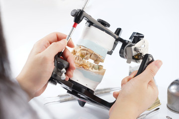 Dental technician working with articulator in dental laboratory