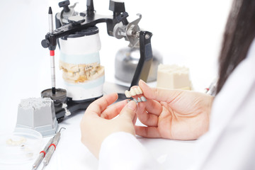 Dental technician working with articulator in dental laboratory