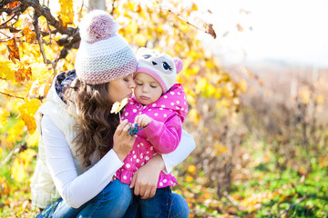 Young mother and her cute girl have fun in autumn vineyard