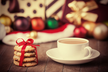 Cookies, cup of coffee with christmas gifts at background